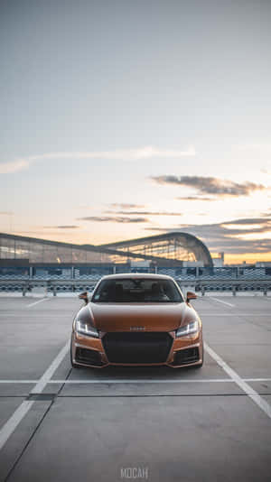 銅色 Audi TT 停喺日落時分嘅空停車場。