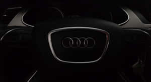 特寫 Audi 標誌在方向盤上，車廂昏暗，配有數碼時鐘。 — 奧迪 GIF 壁紙