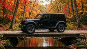 黑色Jeep Wrangler在秋日森林的木橋上，溪流中倒映著色彩繽紛的樹葉
