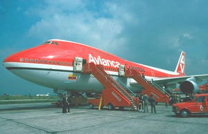 紅白色Avianca Colombia波音747，乘客在機場停機坪通過樓梯登機。