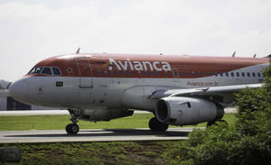 Avianca 飛機在跑道上，附近有綠草和灌木。