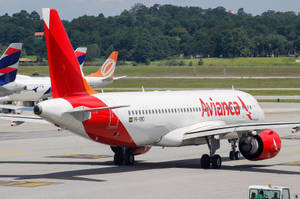 Avianca 飛機在機場停機坪上，背景有綠樹