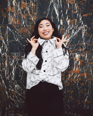 一位穿著圖案襯衫的快樂女性，在大理石牆前愉快地擺姿勢。 — Polo g GIF 壁紙