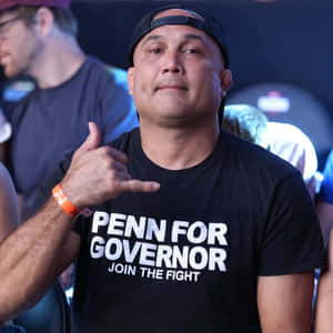 身穿「Penn for Governor」襯衫的男子在活動中做出沙卡手勢。