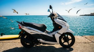 白色電單車停在碼頭上，海鷗在海面上飛翔