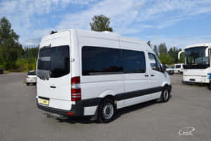 白色 Mercedes-Benz Sprinter 客貨車停泊在戶外停車場，有樹木及其他車輛。 — Surface Pro 壁紙