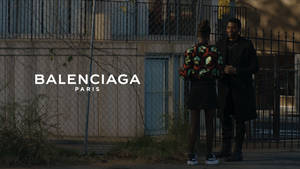 兩位模特兒穿著 Balenciaga 時裝，在日落時站在圍欄附近。 — 巴黎 壁紙