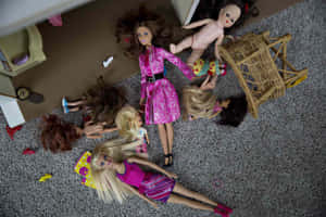 Dolls in pink outfits scattered on a gray carpet after playtime.