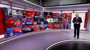 BBC新聞主播在多個視頻屏幕的高科技錄影廠中進行播報。