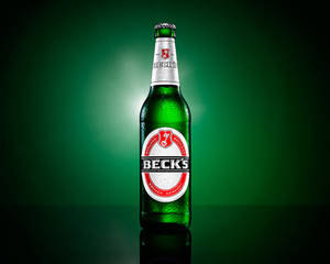 冰凍的 Beck's 啤酒瓶在深綠色反光表面上凝結水珠。