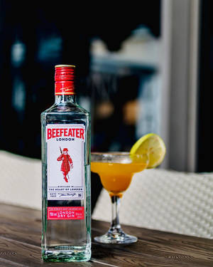Beefeater氈酒瓶和雞尾酒在晚上的木桌上