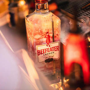 酒吧上的一瓶 Beefeater 氈酒，帶有溫暖的燈光和模糊的背景。