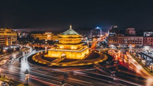 一座歷史悠久的塔樓在夜間被點亮，周圍是繁忙的交通痕跡。