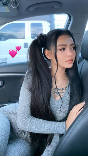穿著灰色毛衣的長黑髮女性坐在車內。