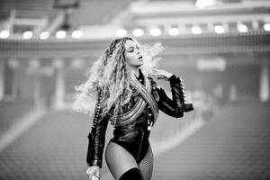 Beyoncé 在明亮的燈光下，身穿皮革服裝，秀髮飄逸，在舞台上表演。