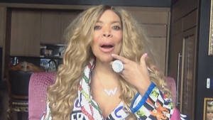 Beyoncé 留著金色捲髮，戴著一個大戒指，坐在室內做手勢。 — 美國 壁紙