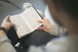 一個人穿著運動鞋坐在室內閱讀一本書。