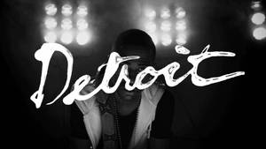 舞台燈光下穿著連帽衫的男子，帶有「Detroit」文字疊加。