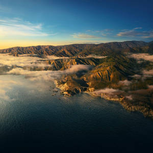日出時分的海岸山脈，山谷中有雲霧，下方是海洋