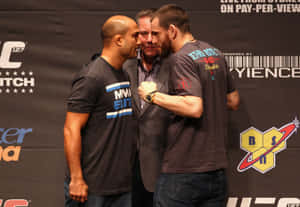 兩名男性MMA拳手在UFC新聞發佈會上對峙，中間有裁判。
