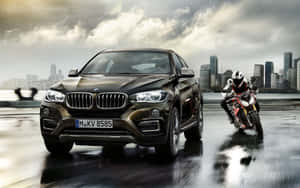 黑色BMW X6和紅色電單車在濕滑的橋上加速，背景是城市天際線。 — Steam Deck 壁紙