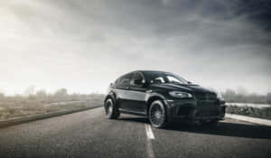 黑色BMW X6M停在鋪砌路上，天空多雲 — 平治 C300 壁紙