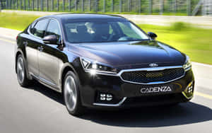 黑色Kia Cadenza轎車在陽光明媚的高速公路上疾馳，背景模糊的綠色植物。 — Steam Deck 壁紙