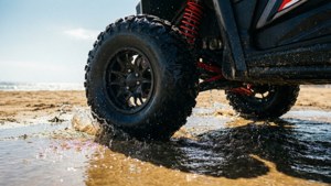 黑色越野車在沙灘上濺起海水。