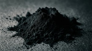 一堆黑色粉末在灰色表面上，帶有戲劇性的照明。