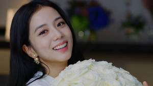 一位微笑的女性在室內手持一束白玫瑰。