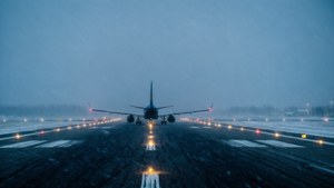 夜間一架飛機在積雪跑道上，雪中有照明引導燈。