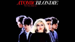 Atomic Blondie 樂團成員穿著西裝，在黑色背景前，帶有紅白文字。