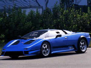 藍色Bugatti EB110超級跑車停在路上，背後有綠色灌木叢。 — 布加迪 壁紙