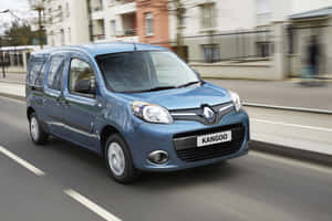 藍色雷諾 Kangoo 客貨車在街道上行駛，帶有動態模糊效果。 — Surface Pro 壁紙