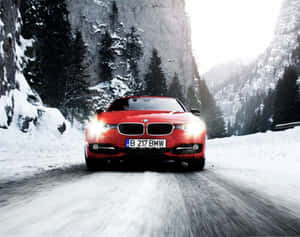 紅色BMW汽車在雪山上快速行駛，有樹木和懸崖。