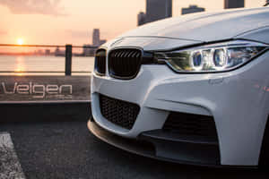 白色BMW跑車在日落時停靠在水邊，背景是城市天際線。