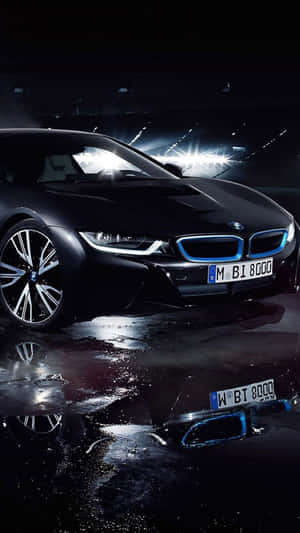 黑色BMW i8跑車，藍色燈光在體育館燈光下反射在潮濕的瀝青路面上。