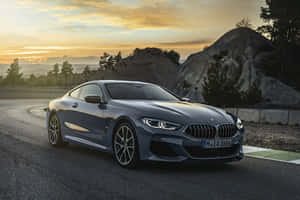 灰色BMW 8系列轎跑車在金色日落時分行駛在蜿蜒的山路上。