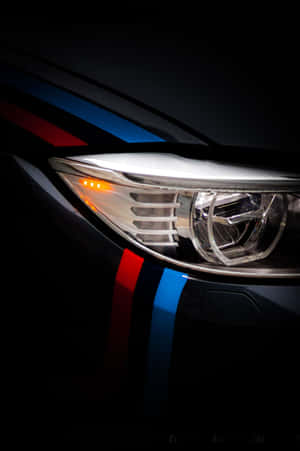 BMW M 車頭燈的特寫，在黑暗環境中帶有賽車條紋。