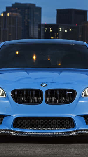 藍色BMW M5跑車停放在黃昏的城市天際線前。