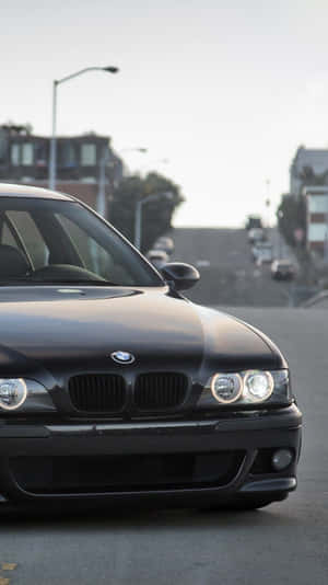 黑色BMW汽車停放在城市街道上，背景有建築物和街燈。