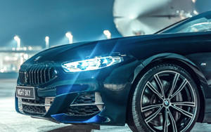 夜間停放的藍色BMW汽車，頭燈發光。
