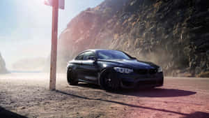 日落時分，黑色BMW M4轎跑車停泊在岩石懸崖旁的塵土路上。