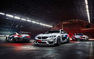 三輛BMW M4 GT4賽車停放在現代化車庫中，燈光效果戲劇化。