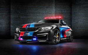黑色BMW M4 Coupe安全車，帶有藍紅白塗裝，在攝影棚燈光下閃耀。