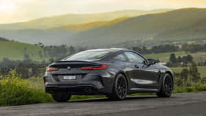 日落時分，深灰色BMW M8 Coupe停泊在風景如畫的鄉村道路上。
