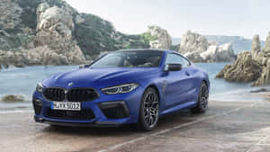 藍色BMW M8 Coupe停泊在石碼頭上，靠近海洋，背景是岩石懸崖。