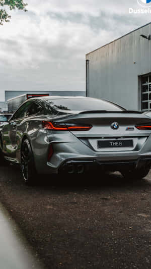 銀色BMW M8 Coupe在陰天停放在工業建築附近。