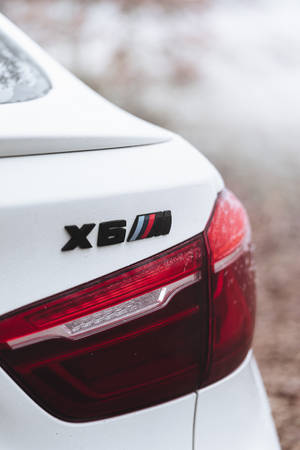 被雪覆蓋的白色BMW X6M後方徽章和尾燈。