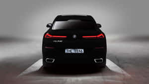 黑色BMW V8X6跑車，帶有發光的紅色尾燈和照明地面圖案。